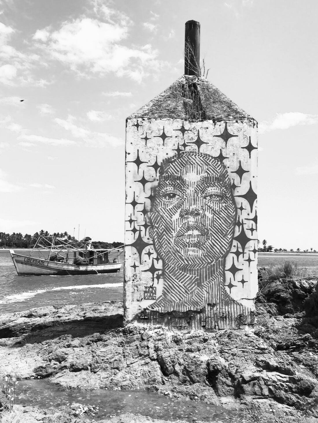 Mural do Izolag com um rosto feminino numa construção à beira-mar